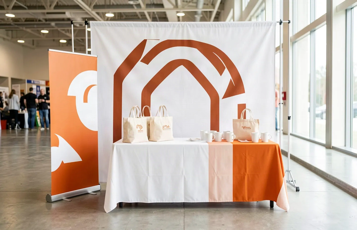 Illustrative orange-and-white event display with a fabric backdrop, banner stand and branded table cover